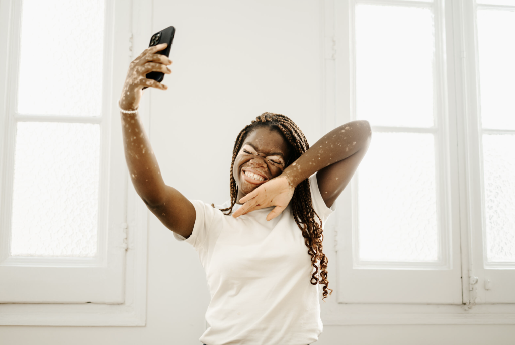 A happy girl is taking a selfie in a well-lit space.
