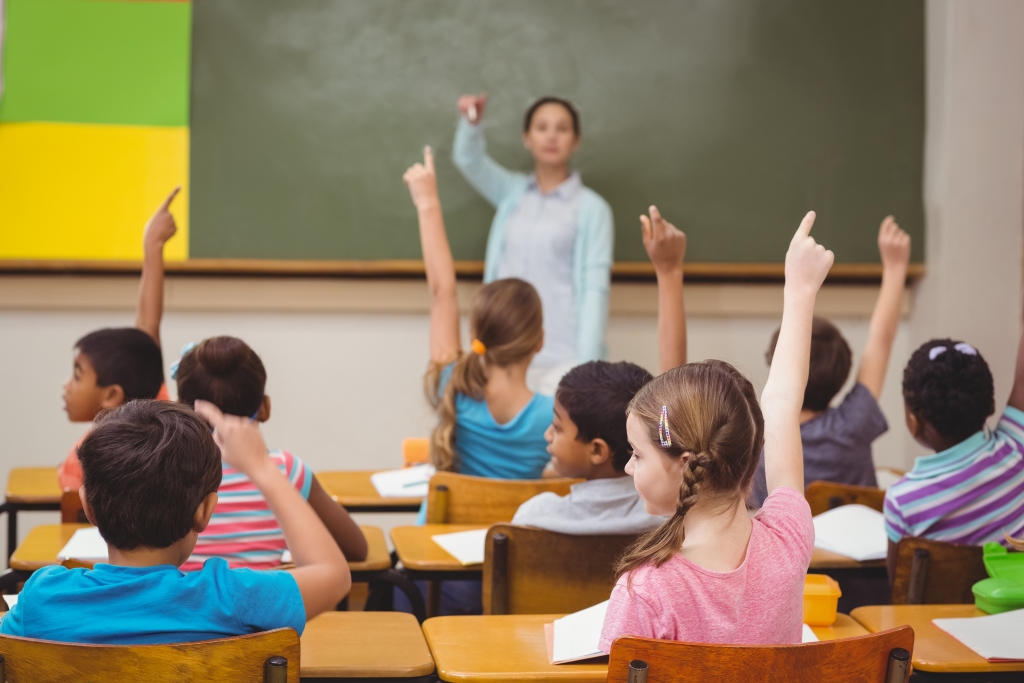 Enseignant dans une salle de classe remplie d'enfants levant la main