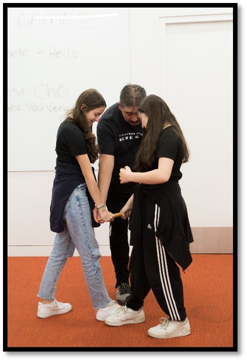 three people standing with one foot touching - A demonstration of the Stick Pull, a traditional Dene Game, at the 2023 National Indigenous Peoples Day Celebration.