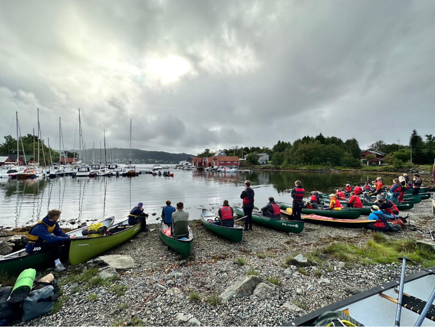 Plusieurs personnes en canoë sont positionnées sur le rivage, s'adonnant à des activités récréatives au bord de l'eau.