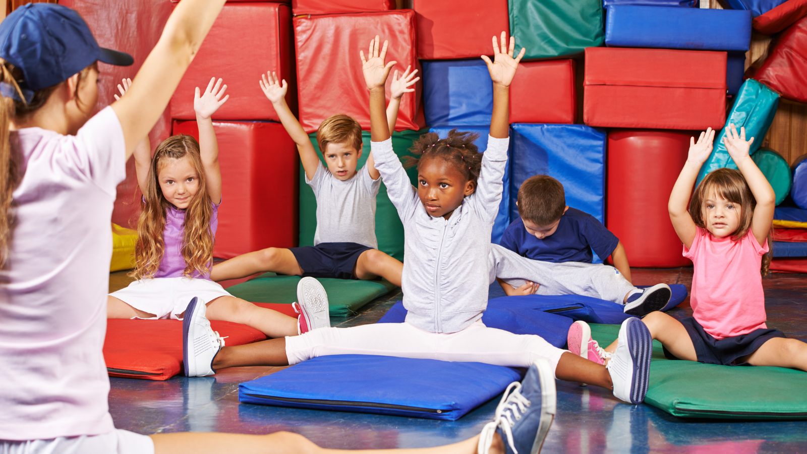 Children practicing various yoga poses in a gym class, demonstrating focus and balance. / Des enfants pratiquent des poses de yoga dans une salle de gym, concentrés et en harmonie avec leur environnement.