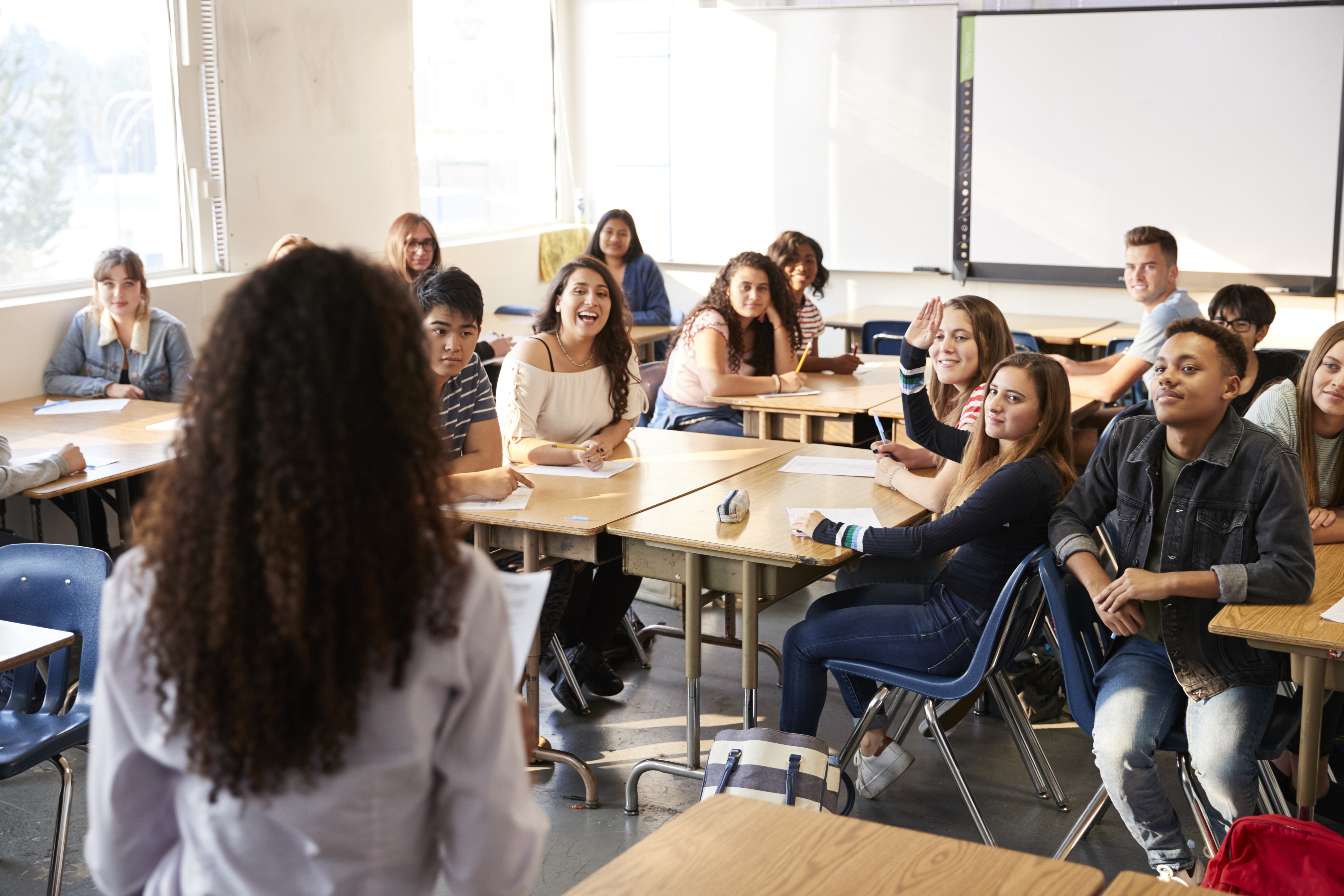 Une salle de classe remplie d'élèves qui sourient en regardant leur professeur.