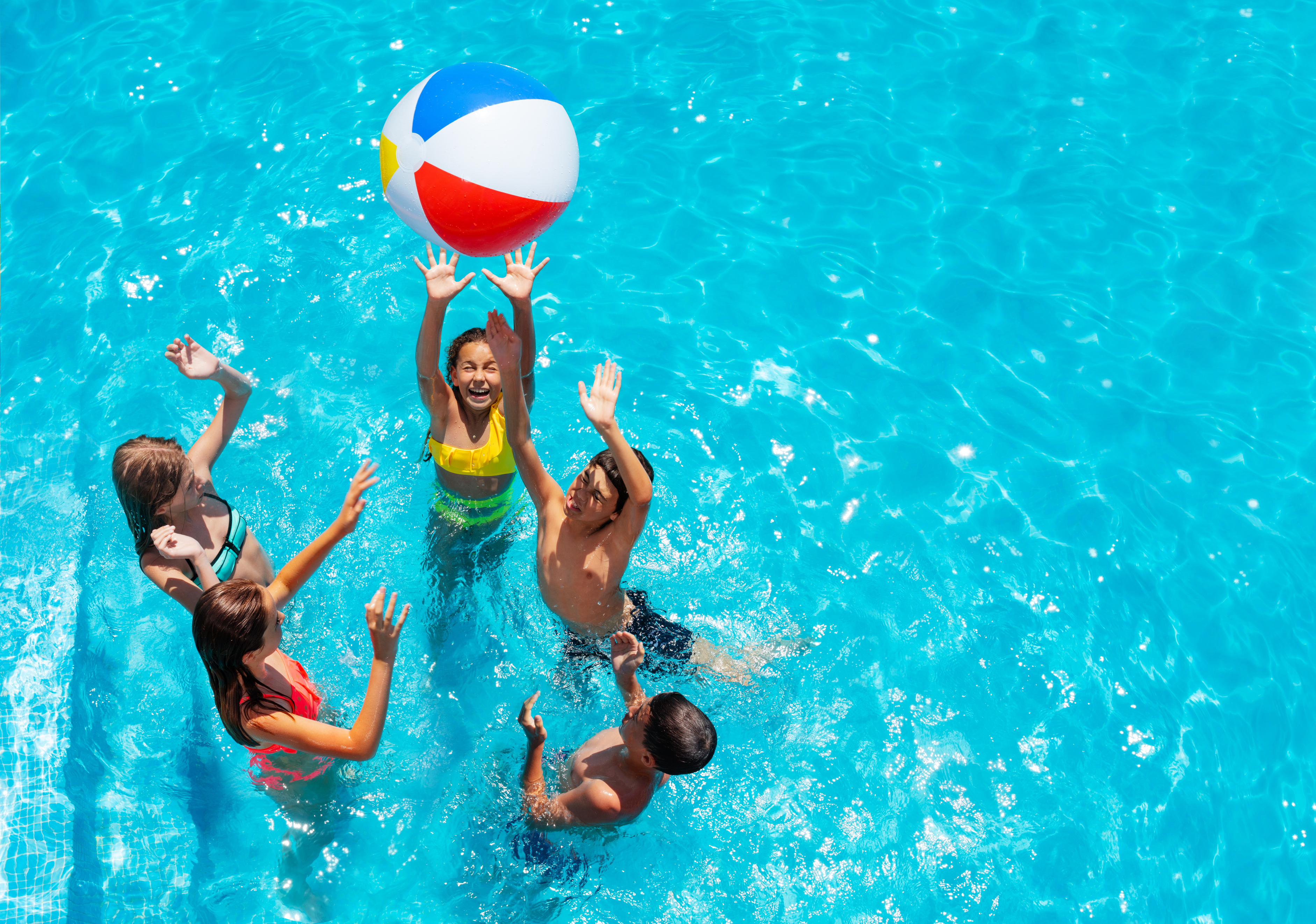 5 children playing in a pool with a beach ball