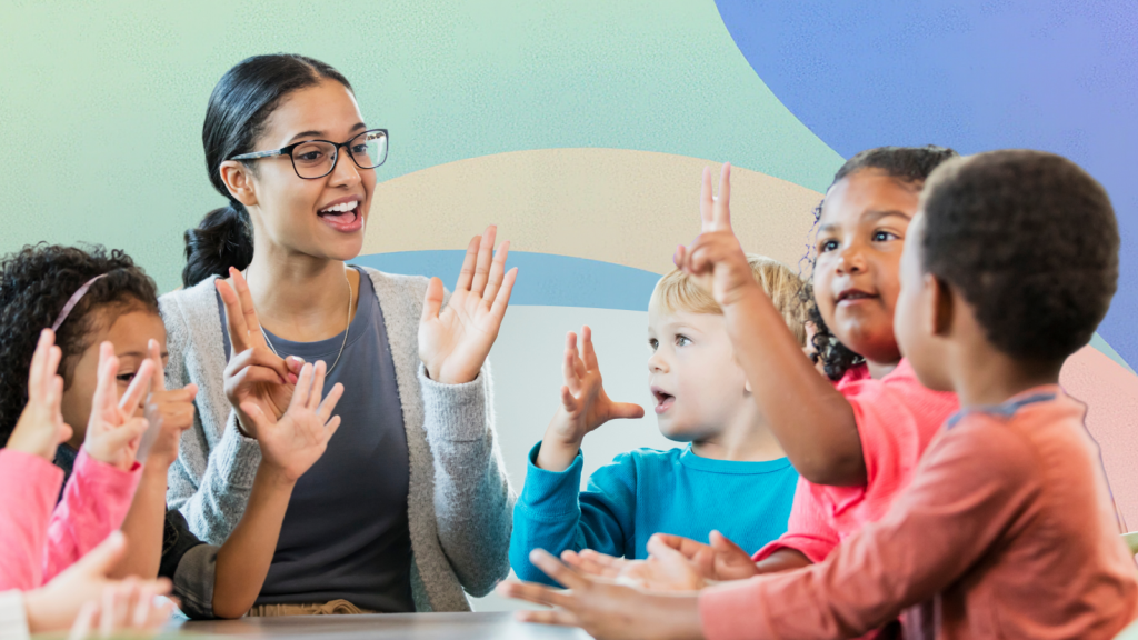 A teacher is sitting with two young children and doing activities using hand gestures. They have smiles on their faces.