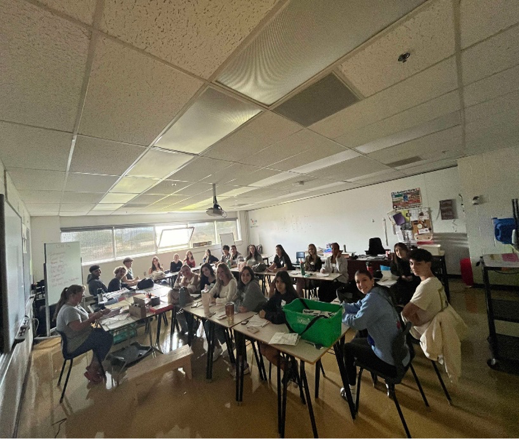 The photo is showing a classroom where students are looking at the camera smiling.