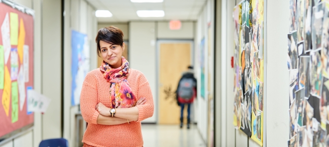 Une femme se tient dans un couloir, les bras croisés, son attitude respirant la confiance et la contemplation.