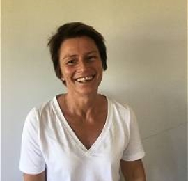 middle aged, woman, with short brown hair, wearing a white v-neck t-shirt