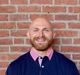 photo of Dyson wearing a dark blue shirt with a pink collar. 