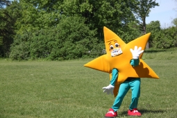 a star mascot standing in a grass field.