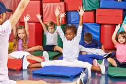 Children practicing various yoga poses in a gym class, demonstrating focus and balance. / Des enfants pratiquent des poses de yoga dans une salle de gym, concentrés et en harmonie avec leur environnement.