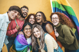 a group of youth smiling with a pride flag 
