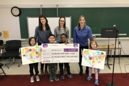 3 adults and 3 children in a classroom holding posters and a cheque for the Share2Care program from PHE Canada