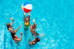 5 children playing in a pool with a beach ball