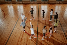 A group of diverse individuals in a gym warming up before practice - Un groupe de personnes d'horizons divers dans une salle de sport, en train de s'échauffer avant l'entraînement