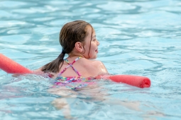 a kid in a swimming pool using a pool noodle