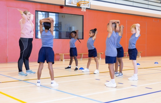A diverse group of children playing and exercising together in a gymnasium setting.