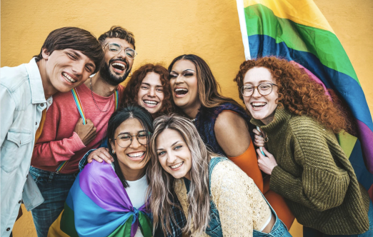 a group of youth smiling with a pride flag 