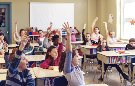 classroom of children with their hands up
