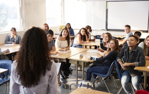 Une salle de classe remplie d'élèves qui sourient en regardant leur professeur.
