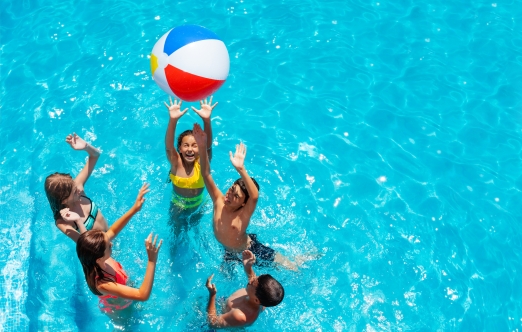 5 children playing in a pool with a beach ball