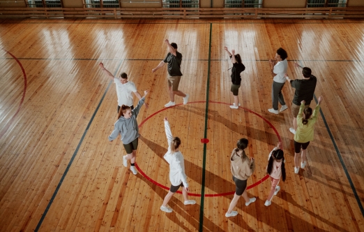 A group of diverse individuals in a gym warming up before practice - Un groupe de personnes d'horizons divers dans une salle de sport, en train de s'échauffer avant l'entraînement